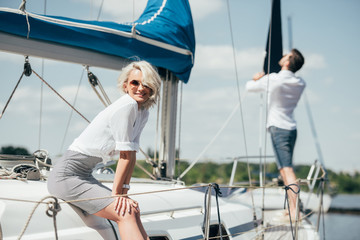 beautiful young woman in sunglasses smiling at camera on yacht