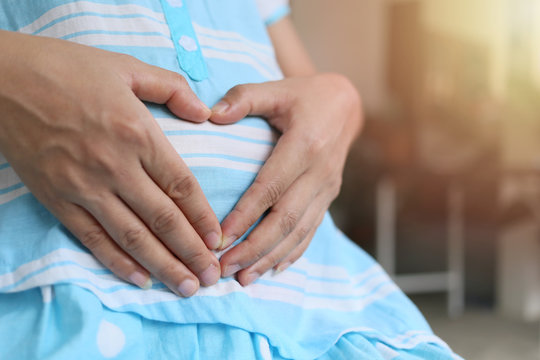 Pregnant mothers use hand to heart shaped on belly.