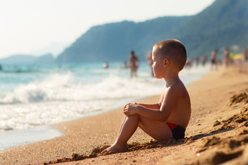 Fototapeta na wymiar Little boy sitting on beach.