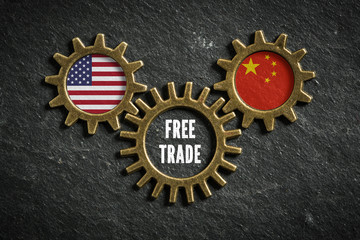 Gears on slate background with the flags of USA and China in it, connected bei a gear with the words "free trade" in it