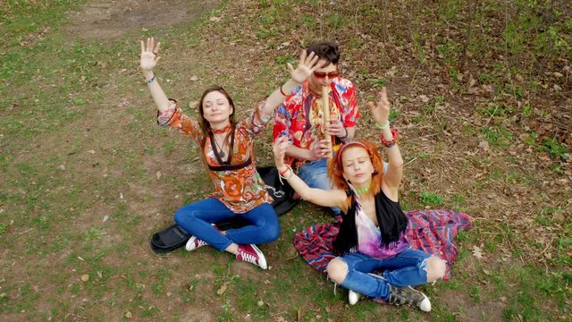 Hippie girls and boy meditates and asks sun for good emotion in the spring forest