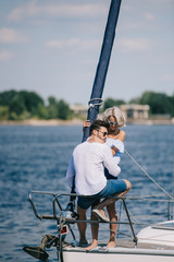 beautiful happy young couple in sunglasses sitting and hugging on yacht