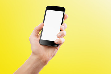 Fototapeta na wymiar Mockup of male hand holding black cellphone isolated at yellow background.