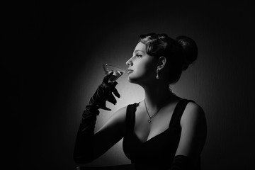 Dramatic portrait of a beautiful woman with glass of martini .