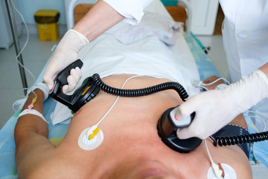 hands of doctor holding defibrillator electrods, performing defibrillation or electropulse therapy