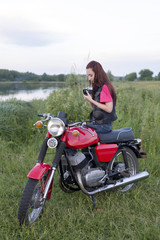 Fototapeta na wymiar Girl sitting on a vintage motorcycle with a camera