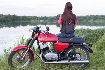 Fototapeta na wymiar Girl with long hair sitting on red vintage motorcycle