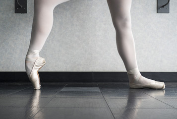 Ballerina in ballet class warming up he pointe shoes, ballet slippers at the barre