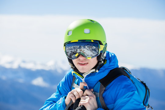 Photo of man in helmet and glasses with reflection of mountains on winter day