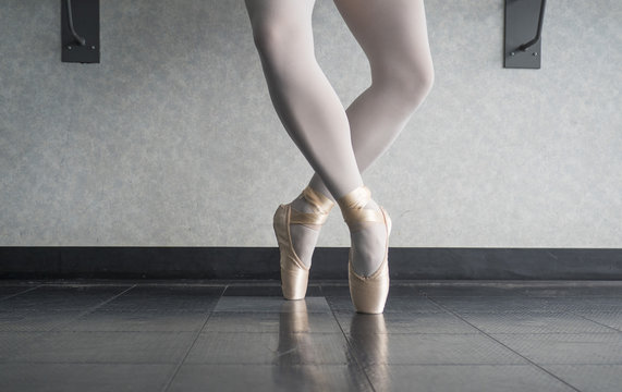 Ballerina dancer in the ballet studio en pointe in releve fourth position 