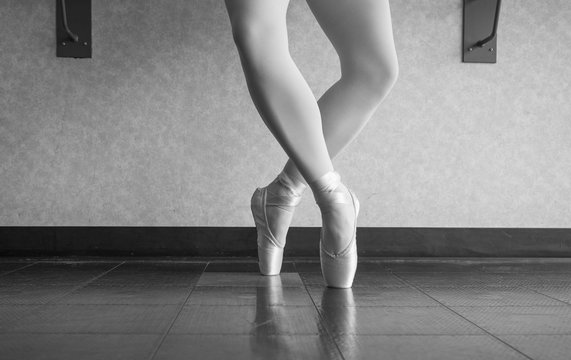 Black and white version of Ballerina dancer in the ballet studio en pointe in releve fourth position 