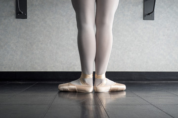 Back view of ballet dancer ballerina at the barre in dance class standing in first position