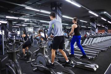 People exercising on training machines in gym