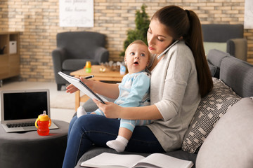 Young mother holding baby while working at home