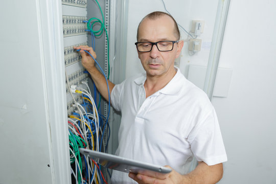 attentive technician fixing cable in server room