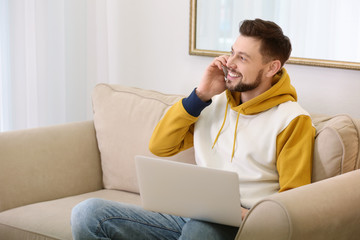 Freelancer talking on phone while using laptop at home