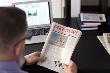 Senior man reading newspaper at work