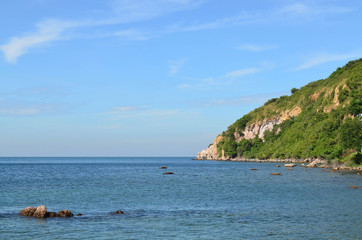 Fototapeta na wymiar Beautiful calm sea with rock and mountain on blue sky day