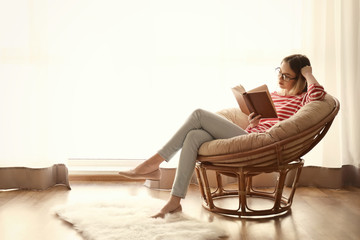 Young woman reading interesting book at home