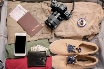Packed suitcase with camera, passport, mobile phone and money. Travel concept