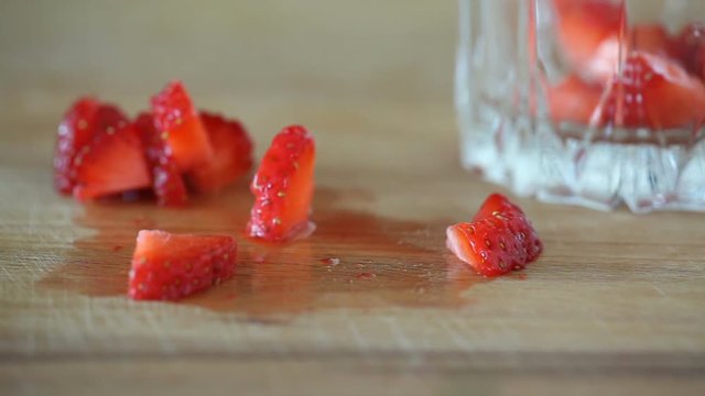 Close-up of putting slices of strawberry into a glass.