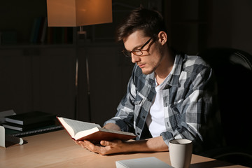 Young man reading book late in evening