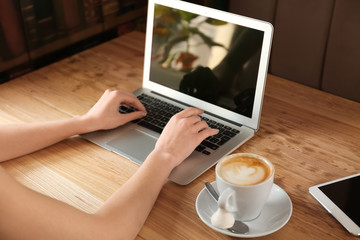 Fototapeta premium Young freelancer with laptop working in cafe
