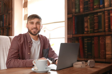 Young freelancer with laptop working in cafe