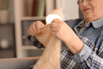 Senior woman knitting sweater at home