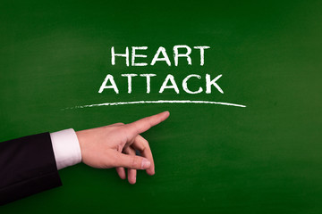 Businessman pointing HEART ATTACK word on blackboard
