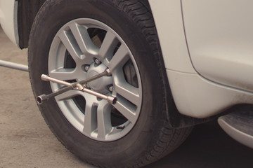 Replacing the wheel on the car. Use a wrench.