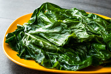 Black Cabbage Leaves / Organic Green Lacinato Kale on Yellow Plate with Grey Granit Surface.