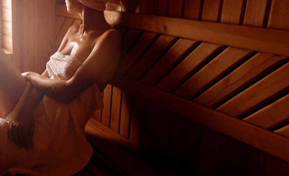 girl in a spa treatment in a traditional sauna with a brush for skin and a washcloth. relaxes wrapped in a white towel