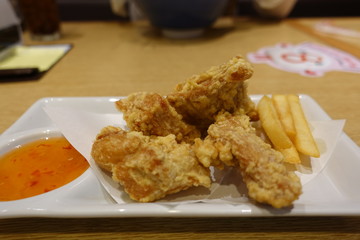 Fried crispy chicken nuggets with french fries and sweet chilli sauce Thai style on white plate