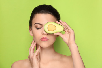Obraz na płótnie Canvas Beautiful young woman with avocado on color background