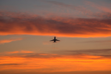 Silhouetted commercial airline over sunset sky