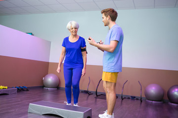 coach controlling step exercise of seniors