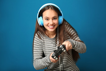 Cute girl with gamepad on color background