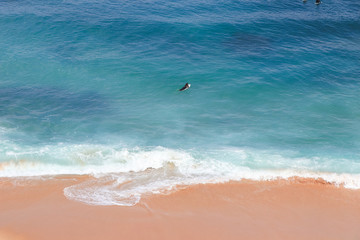 An aerial view of surfer waiting for a wave in the ocean on a clear day