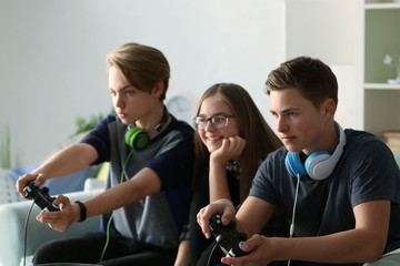 Teenagers playing video games at home