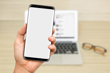 Hand Hold a Smartphone with laptop background