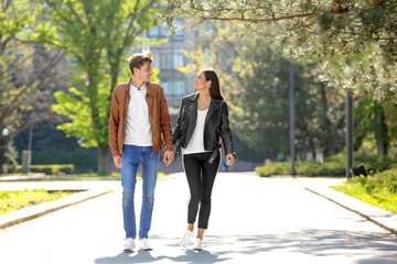 Happy young couple walking together in city park