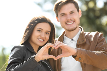 Lovely couple holding hands in shape of heart outdoors