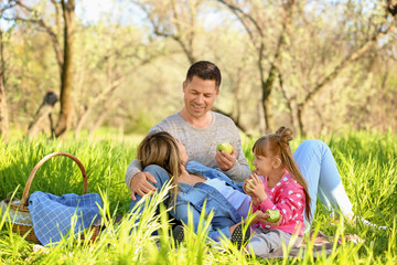 Fototapeta premium Happy family eating apples on a picnic in park