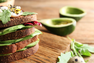 Tasty toasts with avocado on wooden board, closeup