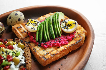 Plate with tasty toasts on light background, closeup