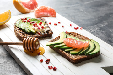 Board with tasty toasts on grey background