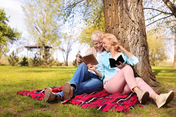 Mature couple reading books in park on spring day