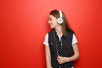 Portrait of beautiful young woman listening to music against color background