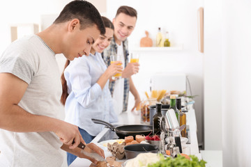 Young man with friends cooking in kitchen